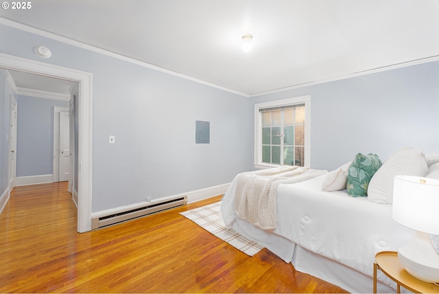 bedroom featuring a baseboard heating unit, wood finished floors, and ornamental molding