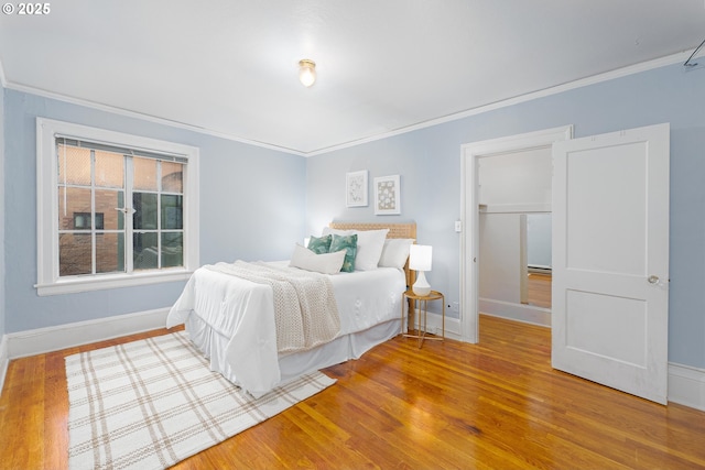 bedroom featuring crown molding, a spacious closet, and wood finished floors