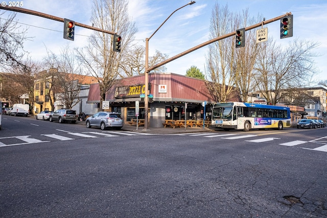 view of street with traffic lights, traffic signs, sidewalks, and street lights