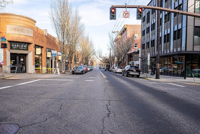 view of road featuring sidewalks, traffic lights, street lighting, and curbs