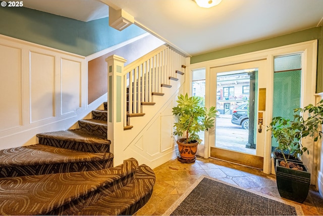 foyer featuring ornate columns, stairway, and a decorative wall