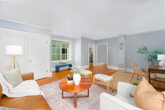 living area with light wood-style floors, crown molding, and baseboards