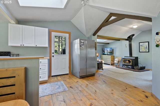 625 Wilson Rd, Mosier, OR 97040 - kitchen featuring freestanding refrigerator, vaulted ceiling, light wood-type flooring, white cabinetry, and a wood stove