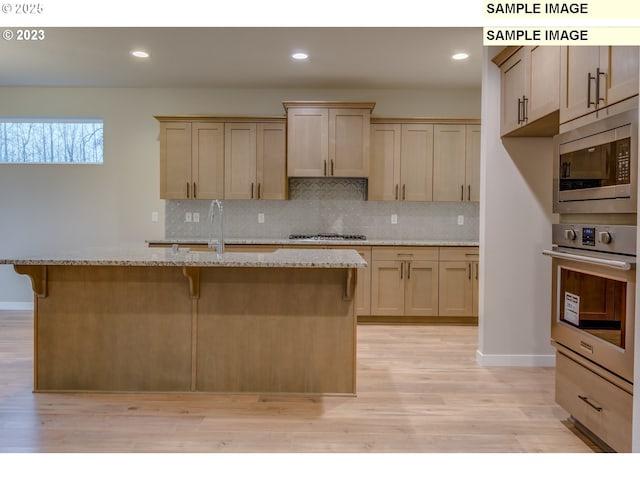 16513 SE Smith Rock St Unit 732, Happy Valley, OR 97086 - kitchen featuring stainless steel appliances, backsplash, a kitchen breakfast bar, light wood-style flooring, and recessed lighting