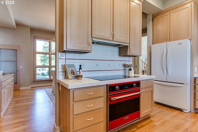 2405 Blacktail Dr, Eugene, OR 97405 - kitchen with freestanding refrigerator, wall oven, light wood-type flooring, tile countertops, and decorative backsplash