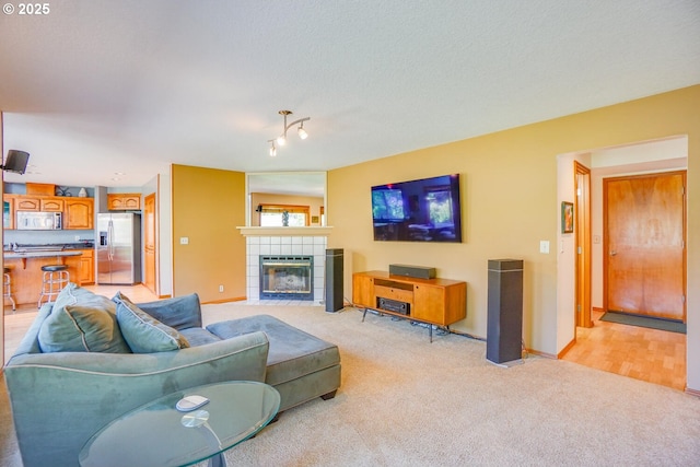 living area with a tiled fireplace, light carpet, and baseboards