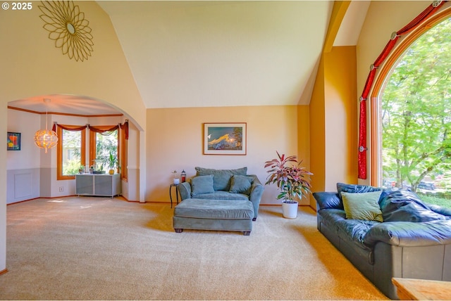 carpeted living area featuring arched walkways, high vaulted ceiling, and a healthy amount of sunlight