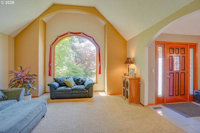 living area with lofted ceiling, a healthy amount of sunlight, carpet floors, and arched walkways
