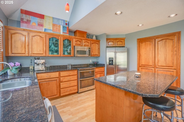 kitchen with light wood-style flooring, a center island, a sink, a kitchen bar, and appliances with stainless steel finishes