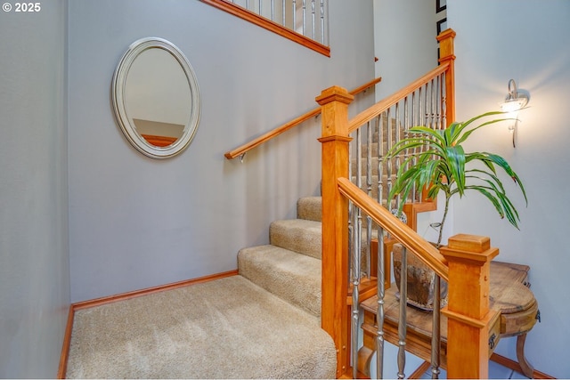 staircase featuring baseboards and carpet
