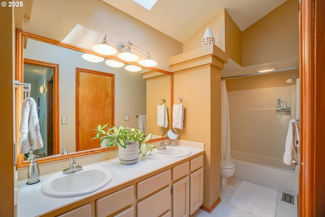 full bathroom featuring double vanity, tile patterned flooring, lofted ceiling with skylight, and a sink