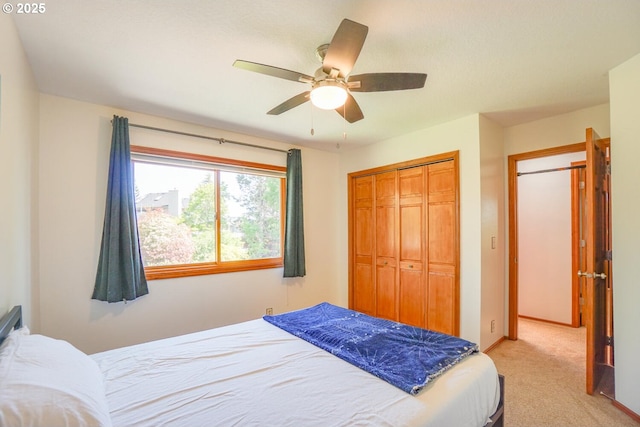 bedroom featuring baseboards, light carpet, a closet, and ceiling fan