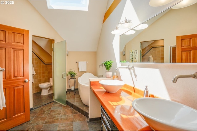 full bath featuring walk in shower, a freestanding tub, vaulted ceiling with skylight, and a sink