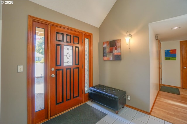 foyer entrance with vaulted ceiling, baseboards, and light tile patterned floors