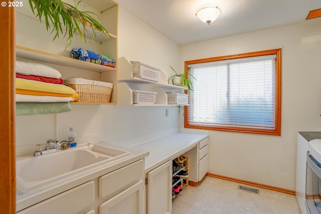 laundry area featuring a sink, cabinet space, visible vents, washer and dryer, and baseboards