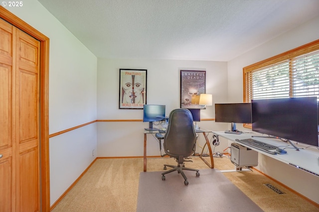 office area with a textured ceiling, carpet, baseboards, and visible vents