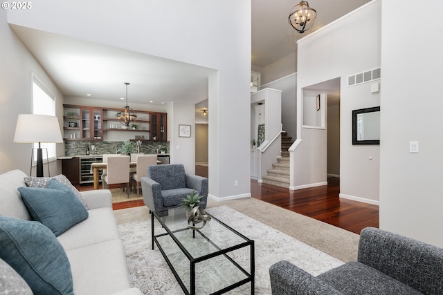 living area featuring carpet floors, visible vents, indoor wet bar, stairway, and a notable chandelier
