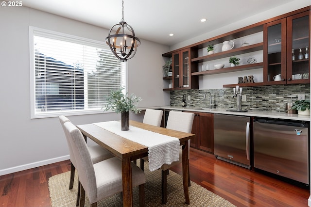 dining space featuring wet bar, baseboards, dark wood-style floors, an inviting chandelier, and recessed lighting