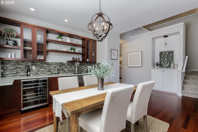 dining space with wine cooler, indoor wet bar, dark wood-type flooring, and a chandelier