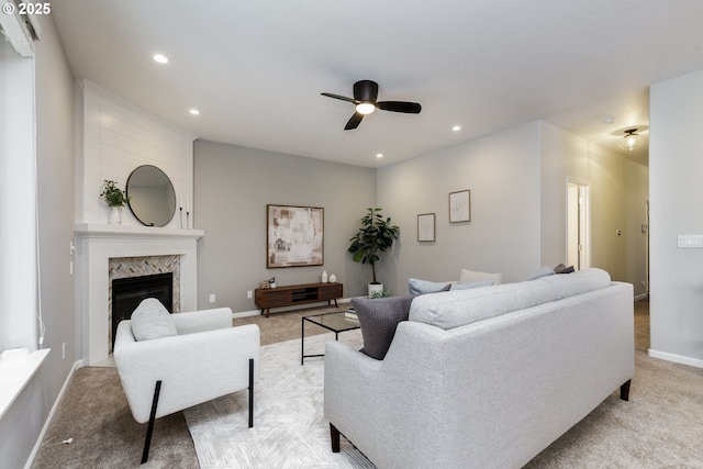 living area with ceiling fan, light colored carpet, baseboards, and a high end fireplace
