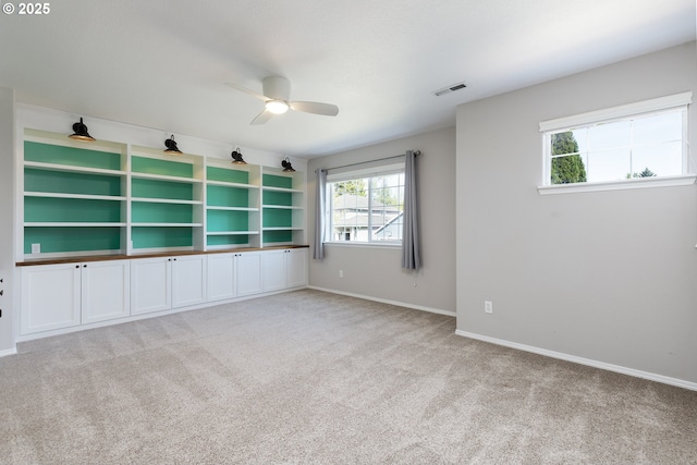 empty room with visible vents, a ceiling fan, carpet floors, and a healthy amount of sunlight