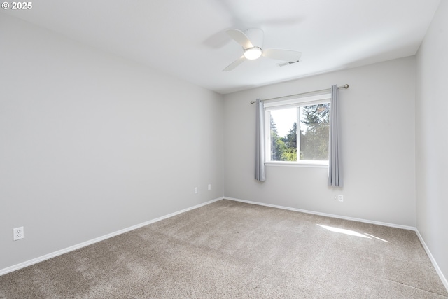 carpeted spare room featuring baseboards, visible vents, and ceiling fan