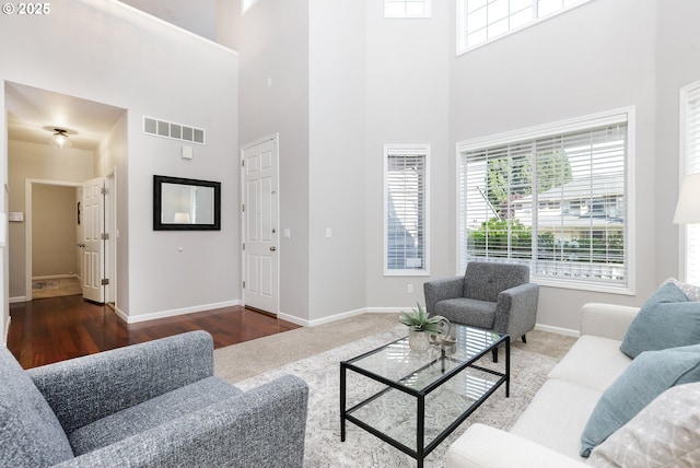 living room featuring visible vents, baseboards, and a towering ceiling