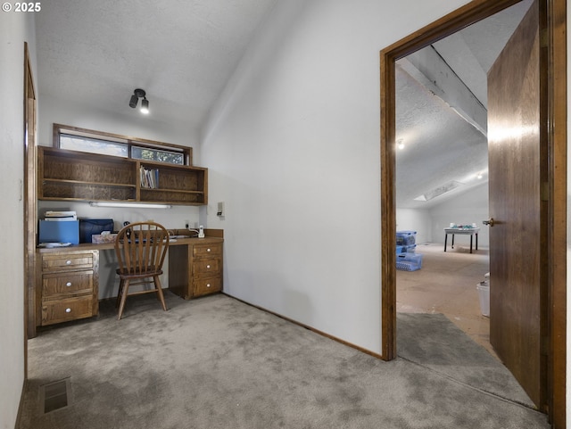 home office with built in desk, vaulted ceiling, carpet, and a textured ceiling