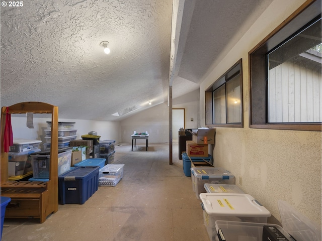 interior space featuring a textured ceiling and vaulted ceiling with skylight