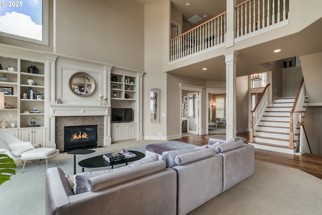 2640 NW Birkendene St, Portland, OR 97229 - living room featuring a high ceiling, decorative columns, a fireplace with flush hearth, stairs, and baseboards