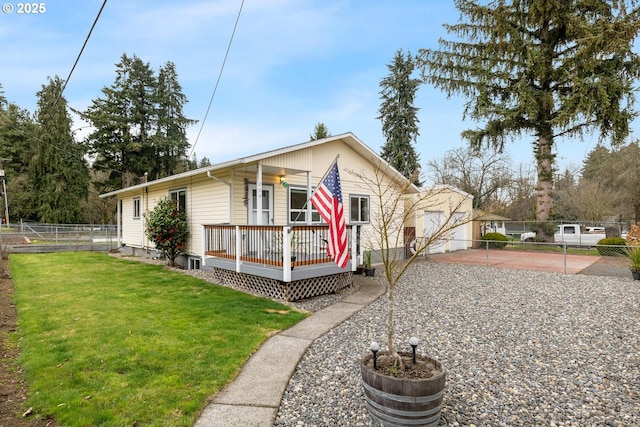 view of front of property featuring a wooden deck, fence, an outbuilding, and a front yard