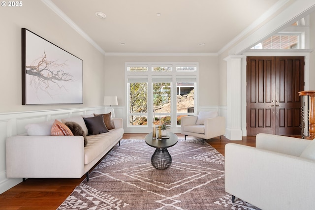 living area featuring a decorative wall, ornamental molding, a wainscoted wall, and wood finished floors