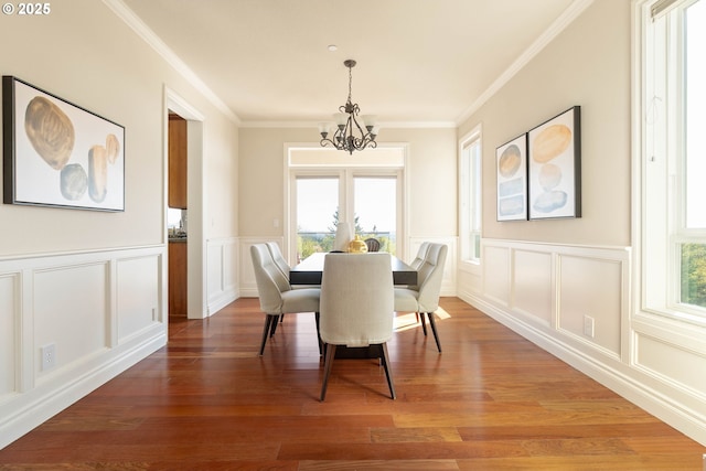 dining space with a decorative wall, ornamental molding, wood finished floors, and a chandelier