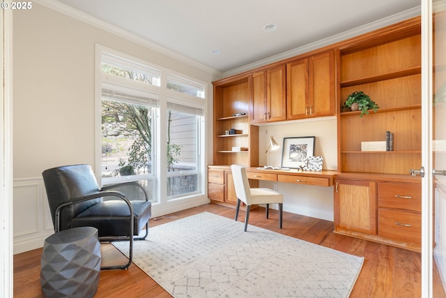 office space featuring built in desk, light wood-style flooring, and ornamental molding
