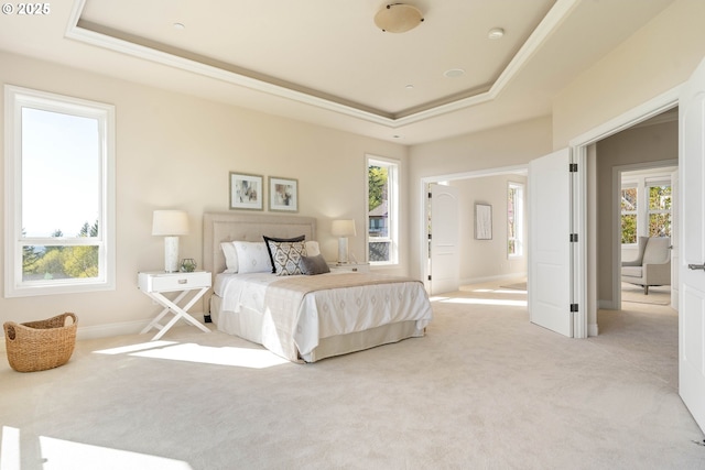 bedroom featuring a tray ceiling, baseboards, light colored carpet, and ornamental molding