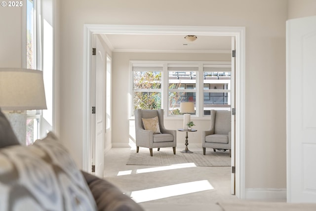 sitting room with carpet floors, crown molding, and baseboards