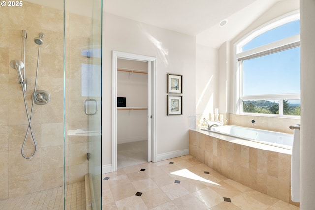 bathroom with a garden tub, tile patterned floors, a stall shower, a spacious closet, and baseboards