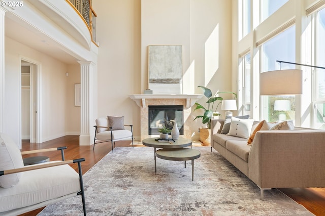 living area with wood finished floors, a towering ceiling, and plenty of natural light