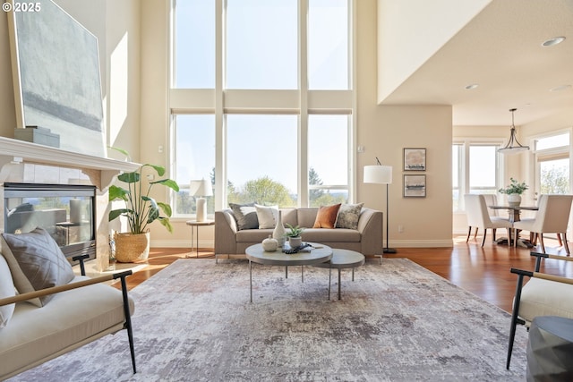living area featuring baseboards, wood finished floors, a high ceiling, and recessed lighting