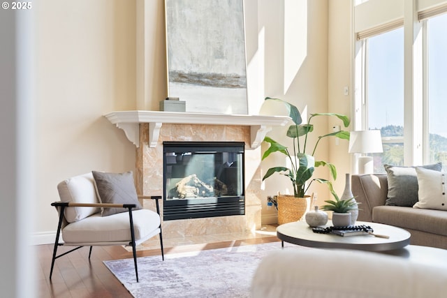 sitting room with a tiled fireplace, wood finished floors, a wealth of natural light, and baseboards