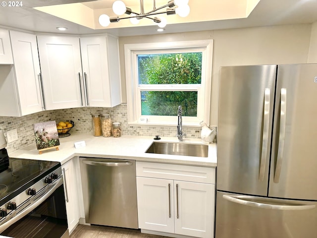 kitchen featuring tasteful backsplash, sink, white cabinetry, appliances with stainless steel finishes, and a chandelier