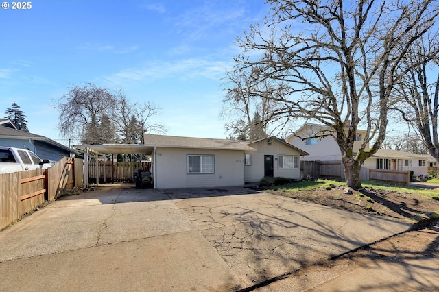 view of front of property with driveway, an attached carport, and fence