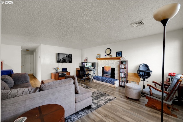 living room featuring hardwood / wood-style flooring, a textured ceiling, and a fireplace