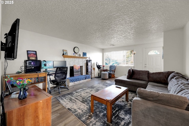 living room featuring a fireplace, wood-type flooring, and a textured ceiling