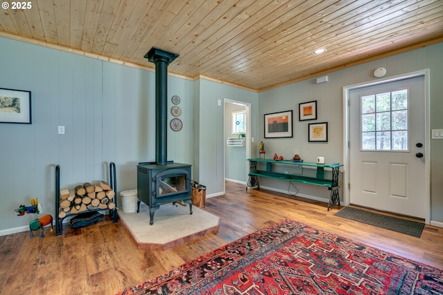 foyer entrance featuring wooden ceiling, a wood stove, and wood finished floors