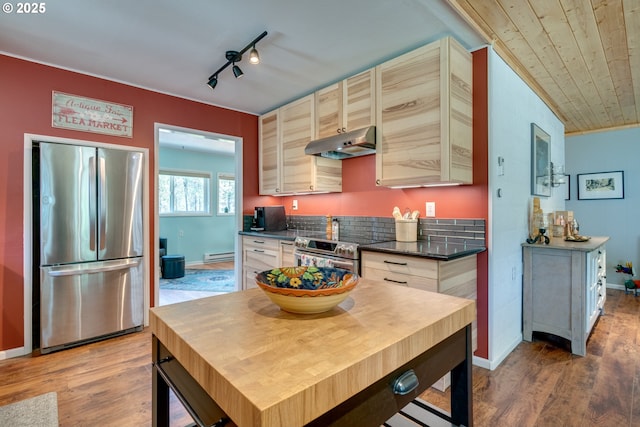 kitchen with dark countertops, under cabinet range hood, light wood-style flooring, appliances with stainless steel finishes, and a baseboard radiator