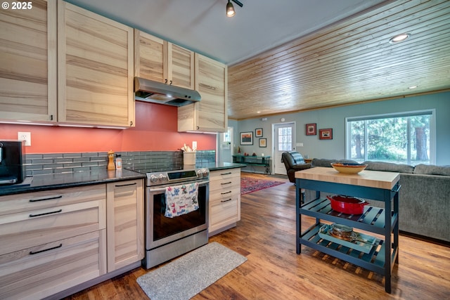 kitchen featuring under cabinet range hood, stainless steel electric range oven, dark countertops, and open floor plan