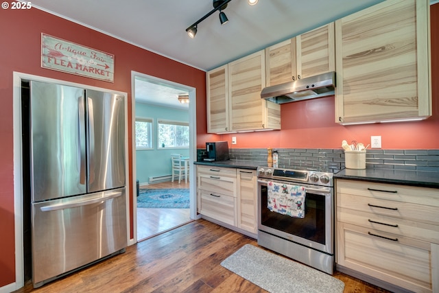 kitchen with dark countertops, light brown cabinets, under cabinet range hood, wood finished floors, and stainless steel appliances