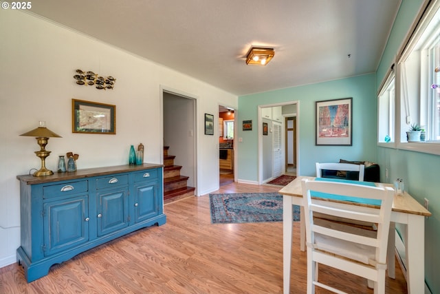 dining space featuring stairway, baseboards, and light wood finished floors