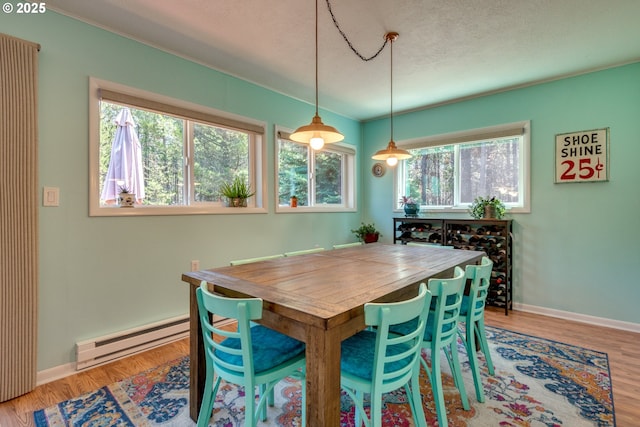 dining room featuring a textured ceiling, wood finished floors, baseboards, and a baseboard radiator